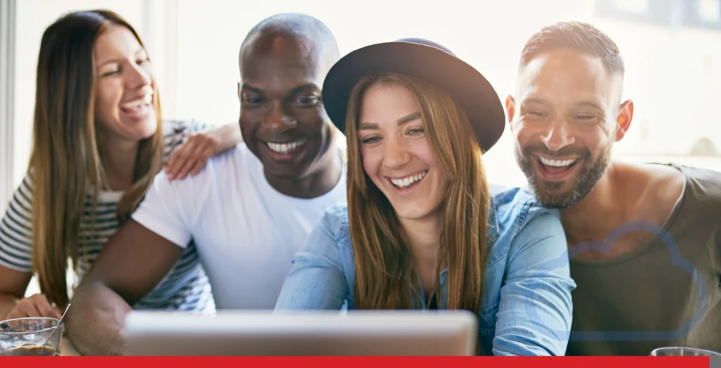 Group of friends looking at a laptop and smiling 