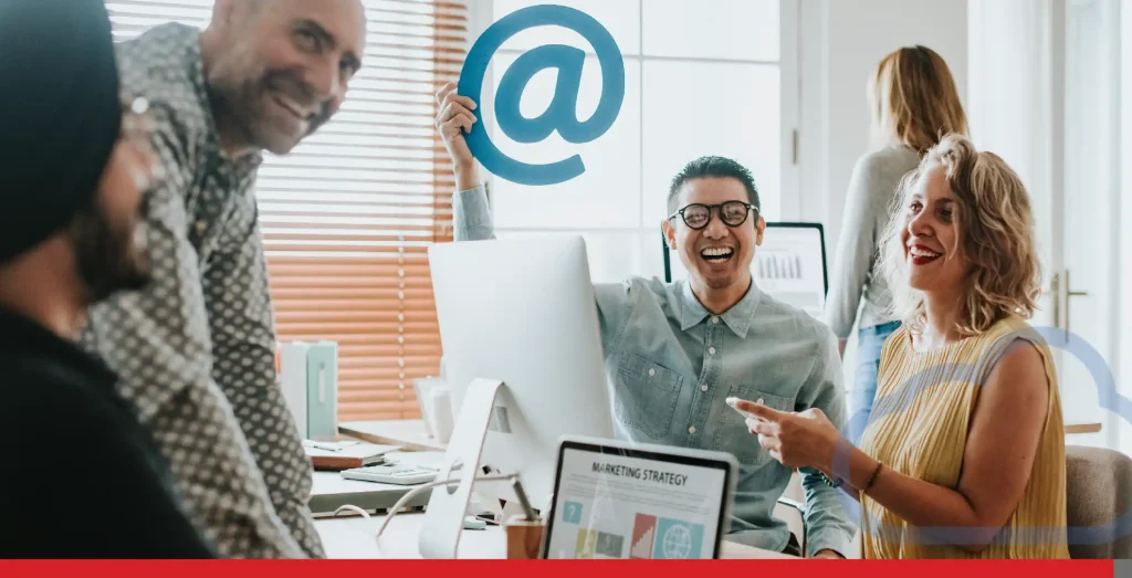 Employees in an office holding an at sign.