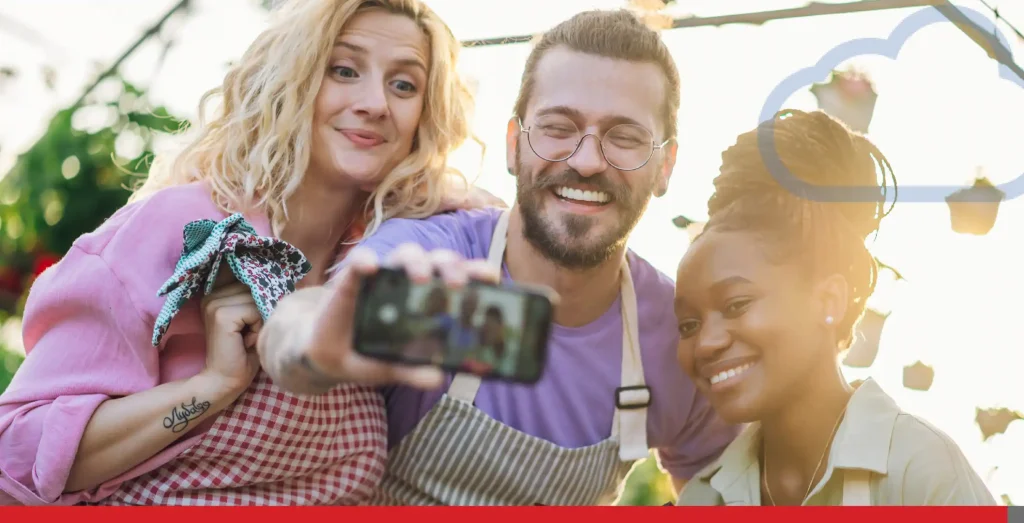 Multiracial group of gardeners working in a greenhouse and taking selfie with a smartphone.