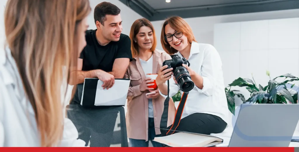 Group of business people in formal clothes indoors in the office looking at photos on the camera