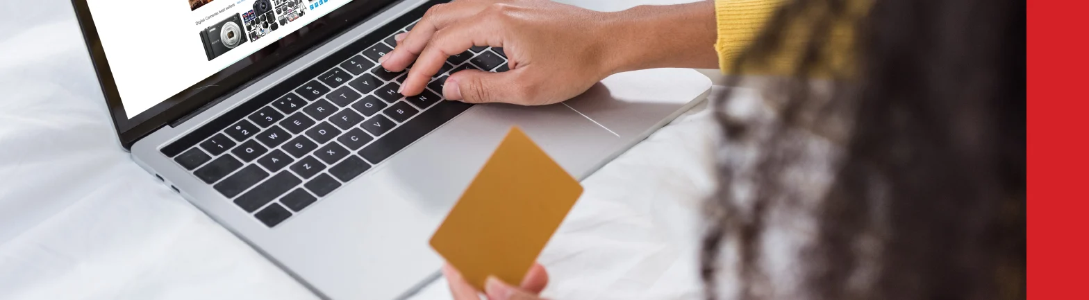 cropped image of woman holding credit card and using laptop with amazon on screen